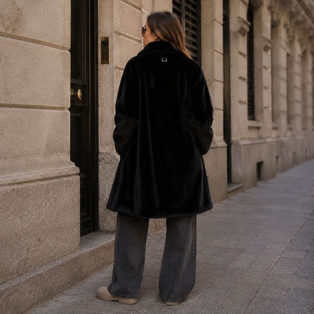 Apparis Blair Coat in Schwarz von hinten getragen, kombiniert mit lässiger Wide Leg Jeans und taupefarbenen Schuhen