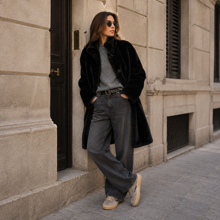Schwarzer Apparis Blair Coat aus weichem Faux Fur kombiniert mit Wide Leg Jeans und taupefarbenen Voile Blanche Sneakern im modernen Streetstyle.