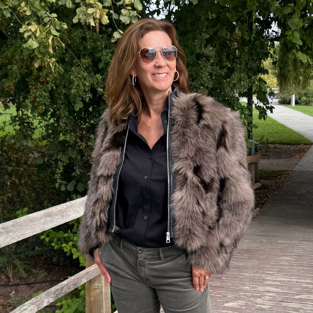 Frau trägt den Patchwork-Bomber LILLET von APPARIS mit Pelzoptik in Beige- und Grautönen, kombiniert mit schwarzer Emotions Bluse.