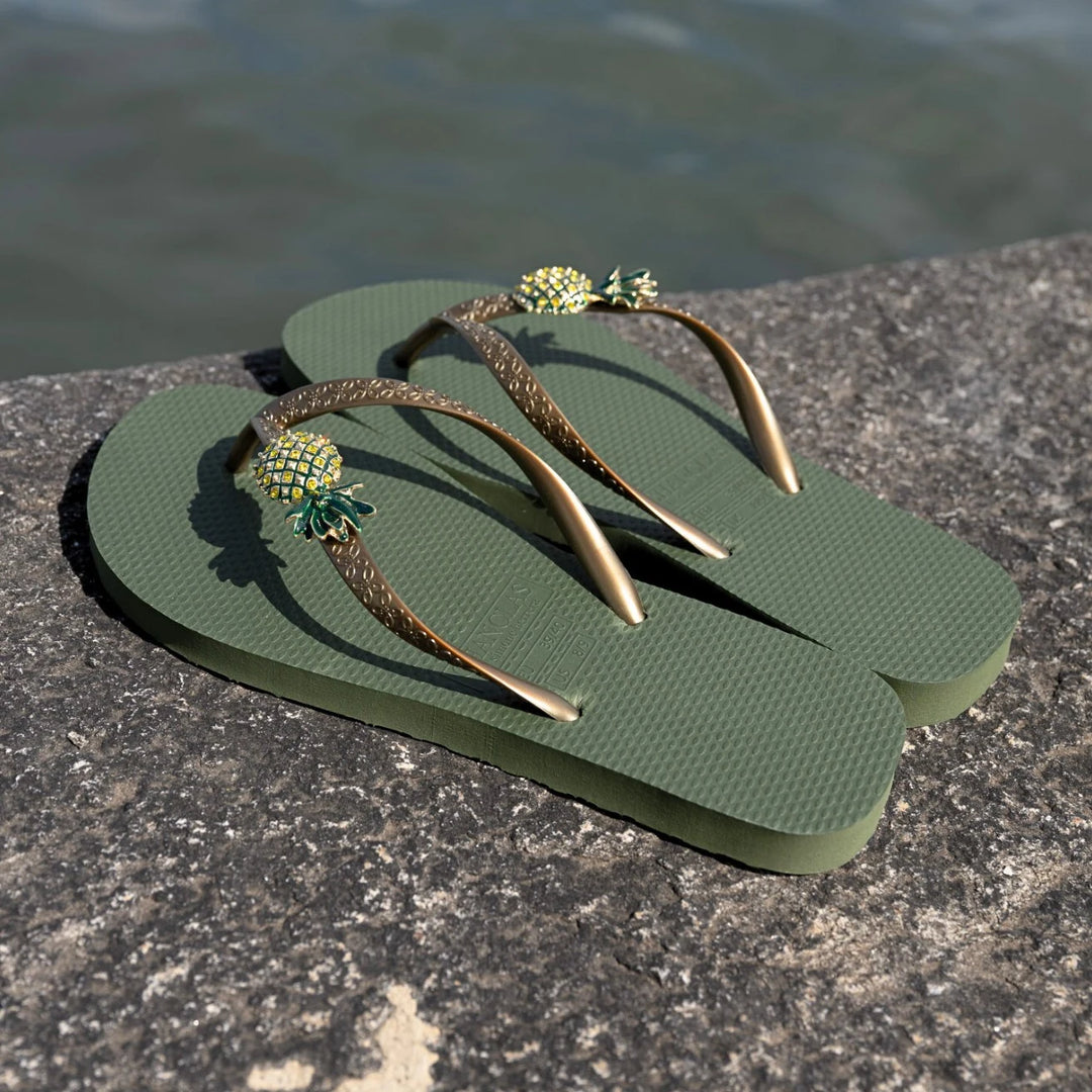 Chanclas by Simone Herrera Livia in Grün mit Ananas-Dekor, Outdoor-Aufnahme der Flip Flops am Wasser.