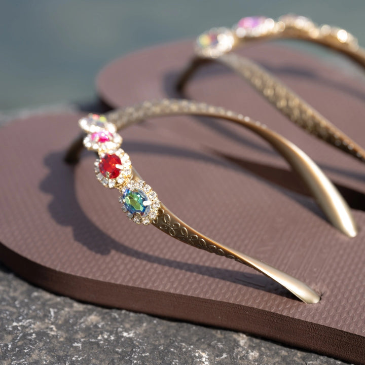 Chanclas by Simone Herrera Antonia in Braun mit Multicolor-Strass, Outdoor-Aufnahme der Flip Flops am Stein.