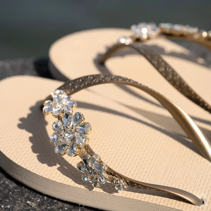 Chanclas by Simone Herrera Celia in Beige mit Diamond-Strass, Outdoor-Aufnahme der Flip Flops am Wasser.
