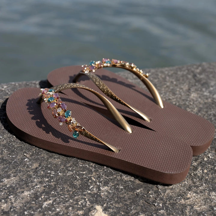 Chanclas by Simone Herrera Chloe in Braun mit türkisen Strasssteinen, seitliche Outdoor-Aufnahme der Flip Flops.