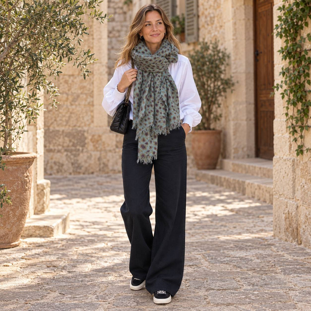 Model trägt Cute Stuff Cashmere Schal Leo Petrol zu weisser Bluse Dunia von 0039 Italy und schwarzer weiter Jeans von THE.NIM mit schwarzen Premiata Sneaker Quinnd