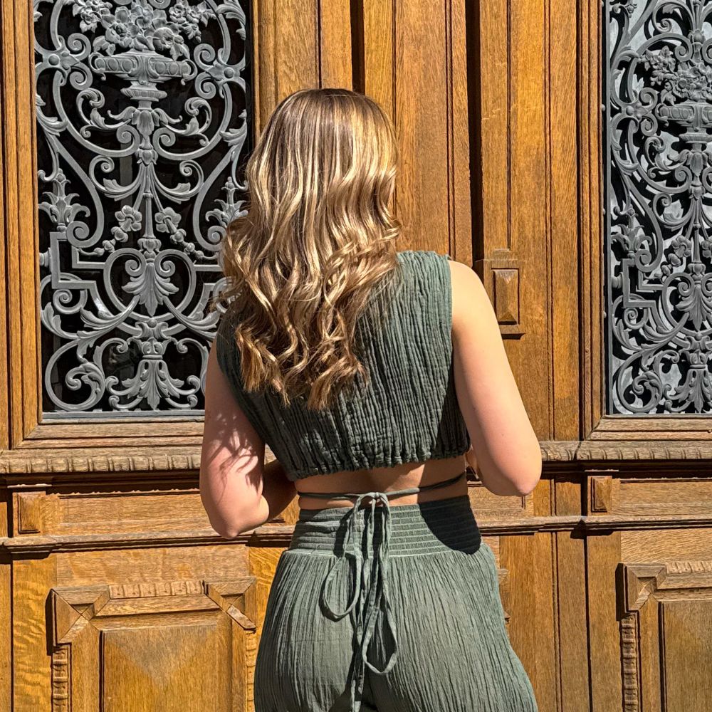 D’ARTEMIDE Alina Top khaki aus Baumwolle, ärmelloses Top mit Bindung in Rückenansicht vor Holztor