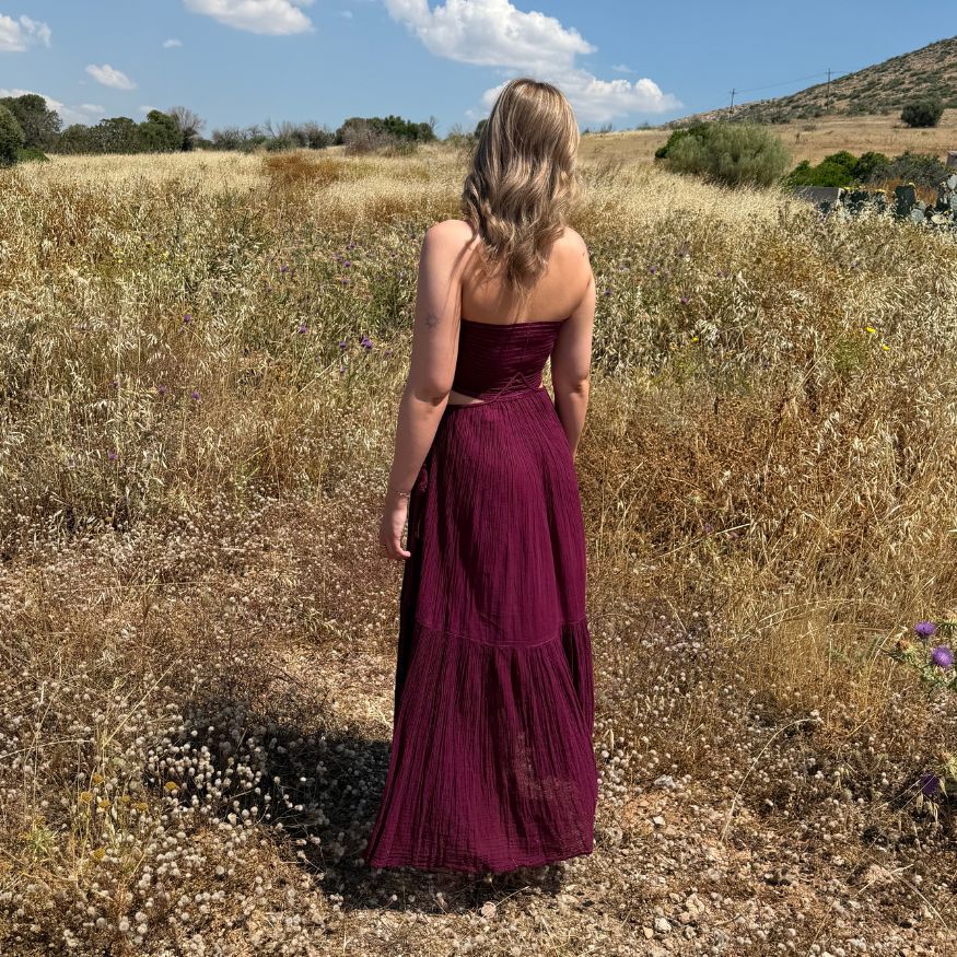 Rückansicht des fliessenden D'Artemide Ava Dresses in Wineberry in einem goldenen Kornfeld in Griechenland