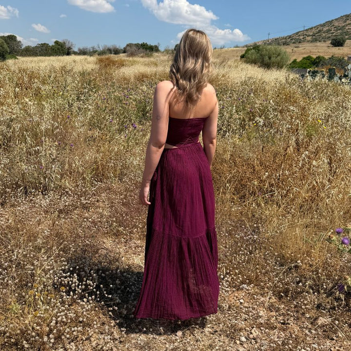 Rückansicht des fliessenden D'Artemide Ava Dresses in Wineberry in einem goldenen Kornfeld in Griechenland