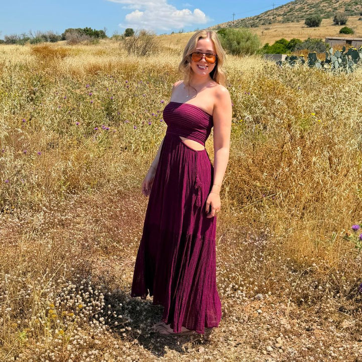 Seitliche Ansicht des D'Artemide Ava Dresses in Wineberry vor sommerlicher Naturkulisse in Griechenland