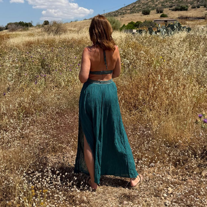 Rückansicht des D'Artemide Idylle Dresses in Emerald zwischen goldenen Kornfeldern und mediterraner Landschaft in Griechenland