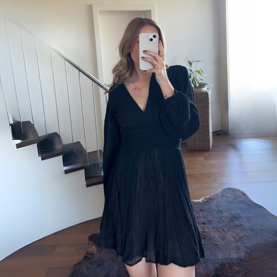 D’ARTEMIDE Nephele Dress Mini in black aus 100 % Baumwolle, kurzes Sommerkleid mit V-Ausschnitt, frontal getragen im Innenraum