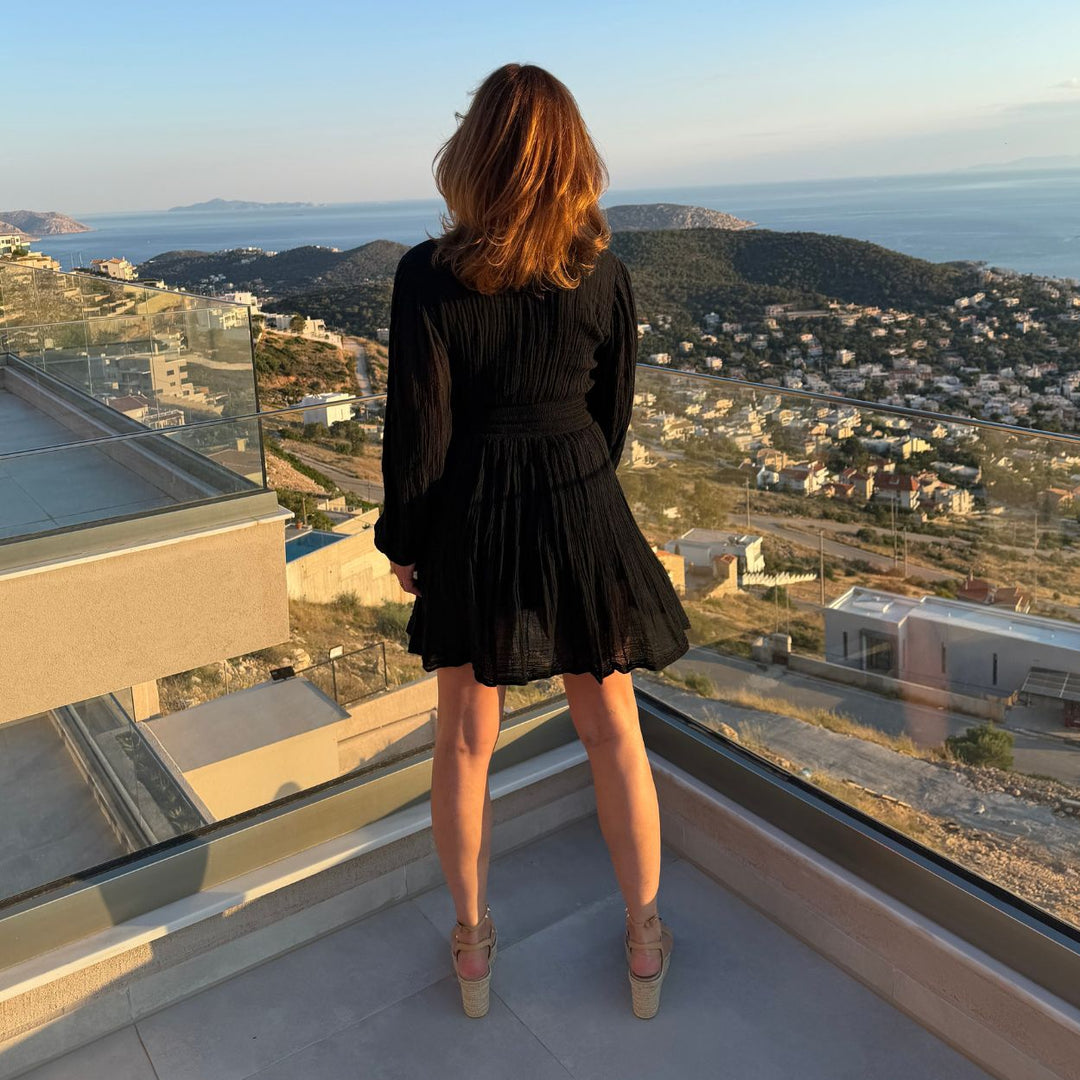 Rückenansicht des schwarzen D'Artemide Nephele Mini Dress auf Terrasse mit Küstenpanorama