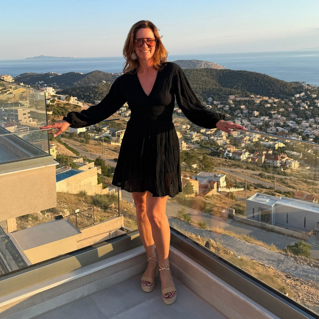 D'Artemide Nephele Mini Dress in Black getragen von Janine auf sonniger Terrasse mit Meerblick in Griechenland