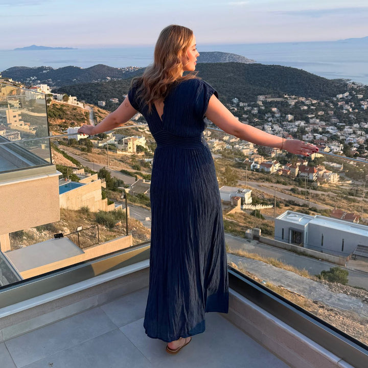 Rückansicht des Artemide Nerea Rückansicht des D'Artemide Nerea Dresses in Dark Blue auf einer Terrasse über der griechischen Küstenlandschaft