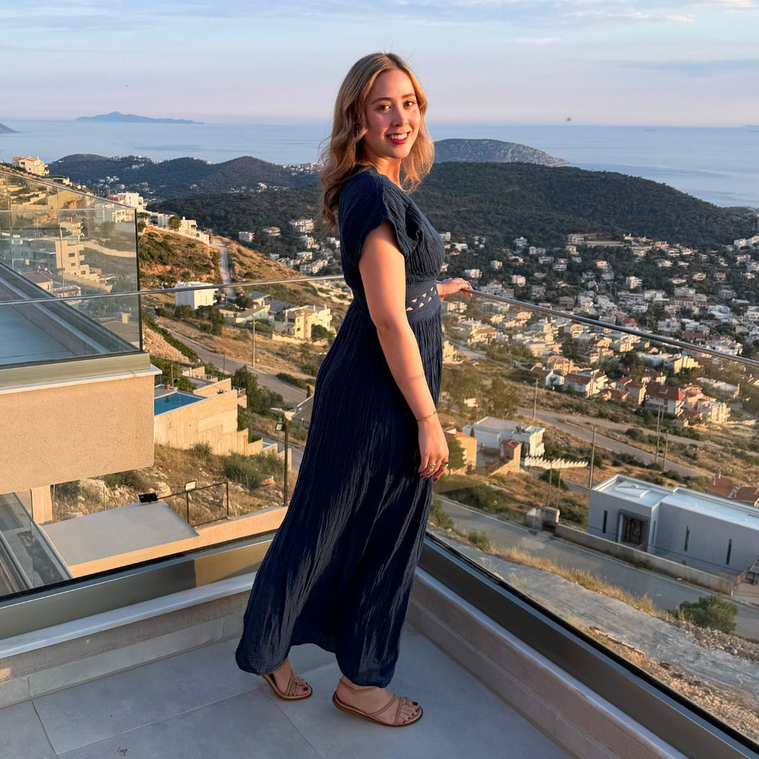 Seitliche Ansicht des dunkelblauen D'Artemide Nerea Dresses auf einer mediterranen Terrasse mit Meerblick in Griechenland