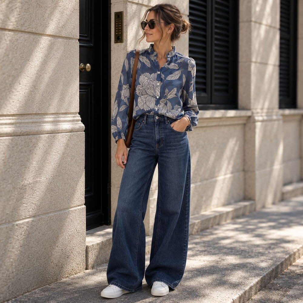 Emotions Bluse Blue Flower aus leichter Baumwolle mit floralem Muster, kombiniert mit dunkelblauen Wide-Leg Jeans, weissen Lemargo Sneakern und brauner Handtasche.