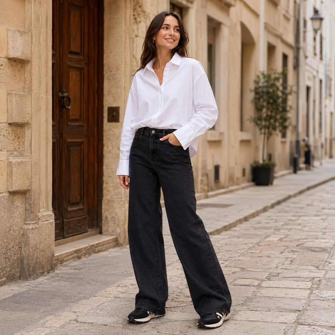 Emotions Oversize Bluse in Weiss, kombiniert mit schwarzer THE.NIM Jeans und Premiata Sneakern auf dem Gehsteig einer Strasse