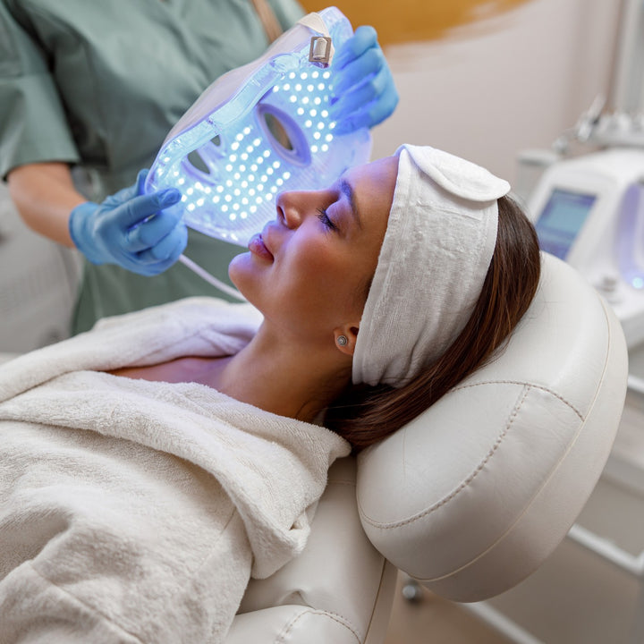 Frau erhält eine LED-Lichttherapie im Gesicht während einer professionellen Behandlung.