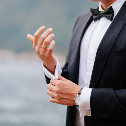 Bräutigam im Smoking richtet Manschette als Symbolbild für gepflegte Hände zur Hochzeitsvorbereitung.