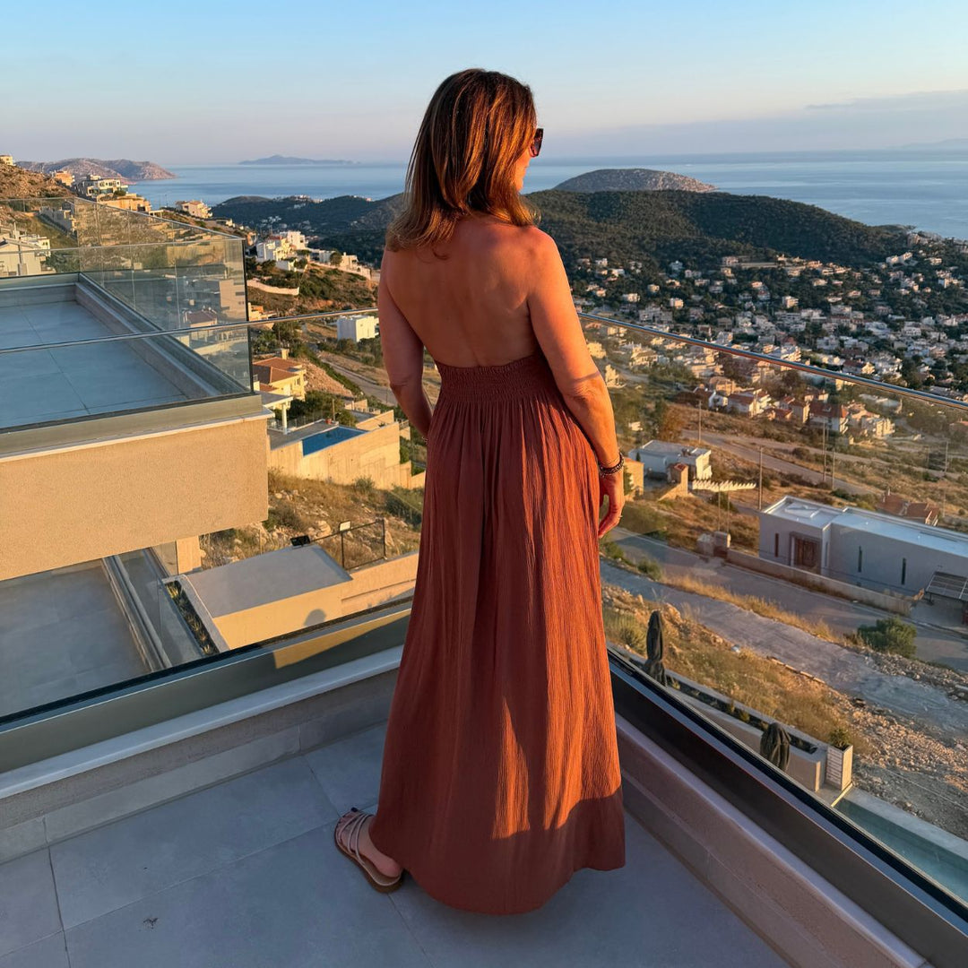 Hot Lava Dress Saba Brown Maxikleid Rückenansicht mit Trägern fliessendes Sommerkleid auf Terrasse mit Meerblick