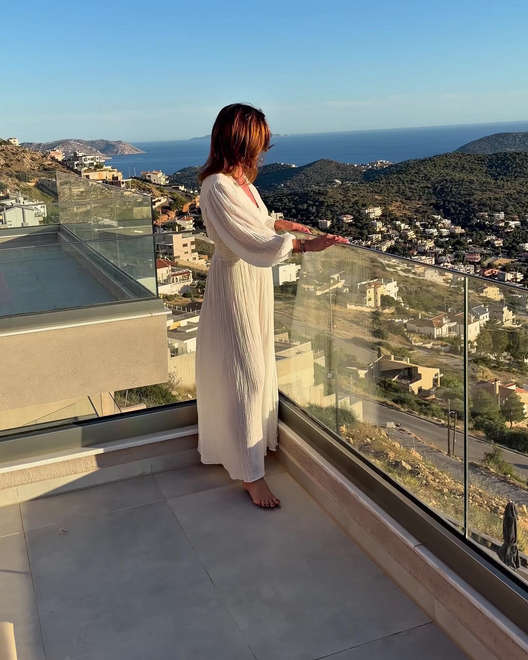 D'Artemide Nephele Dress Ivory in Bewegung auf einer Terrasse mit Panoramablick auf das Mittelmeer