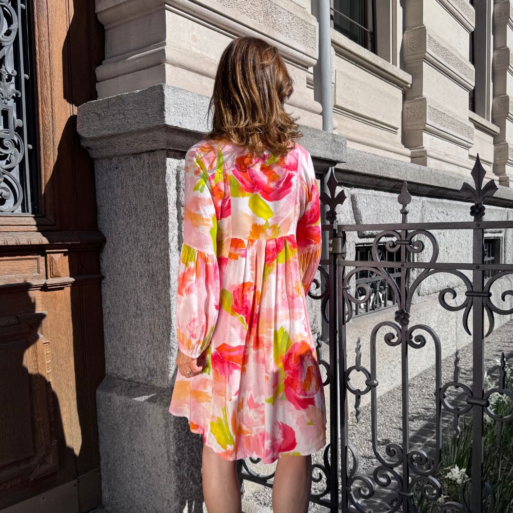 Salty Skin Tunika rot-gelbe Blumen aus Viscose, locker geschnittene Tunika in Rückenansicht vor Stadtfassade